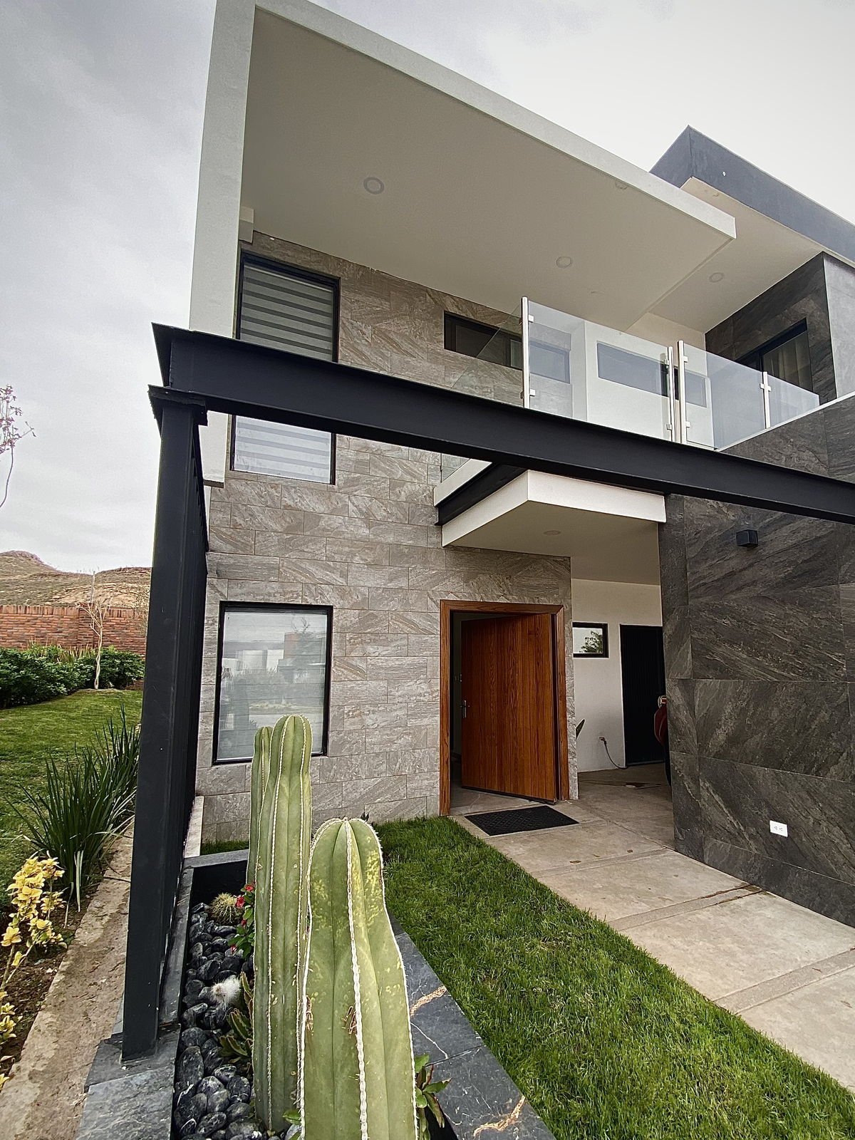 Acceso terminado de Casa Venado, con recubrimiento de piedra natural y jardinería de cactáceas
